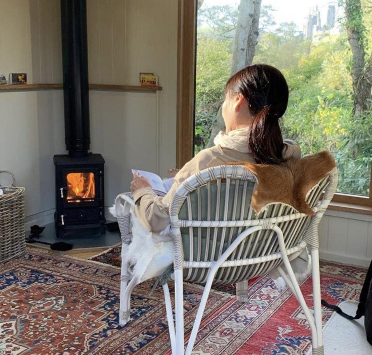 Woman reading besides a woodburner in a shepherds hut