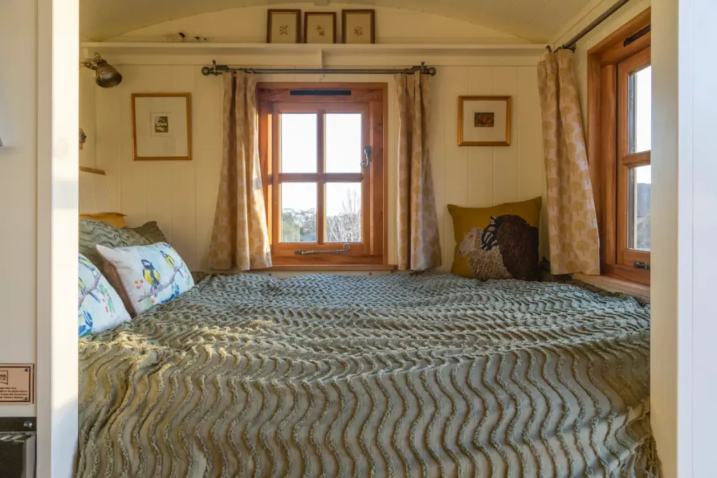 Photograph showing the comfortable kingsize bed with sun pouring in through the window.