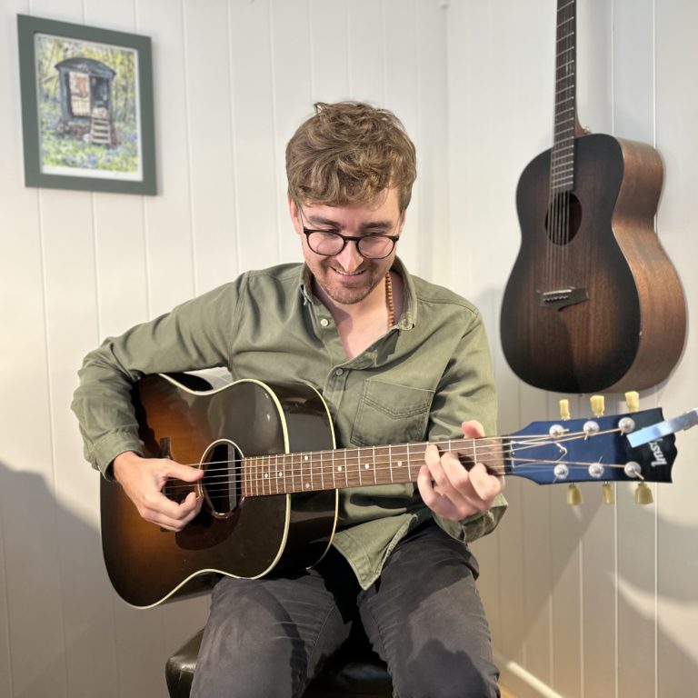 Playing guitar in a Plankbridge shepherd's hut